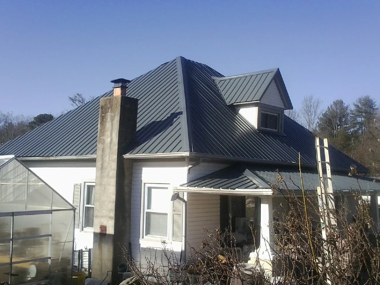 Dark blue standing seam metal roof on a white farmhouse with dormer — Slate & Tile Roof Repair by Roofing Brothers in Delaware City