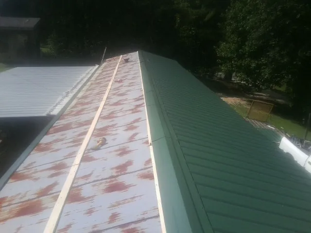 Old rusted panels beside newly installed green metal roofing — Wind Damage Roof Repair by Roofing Brothers in Delaware City