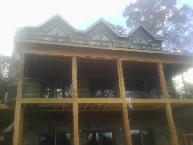 Dormers and porch framing on a large log home under construction — Roof Coating work by our crew in Delaware City