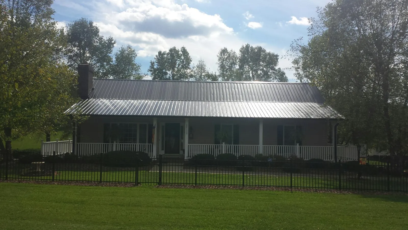 Gray metal roof on a brick ranch with a full width front porch — Gutter Guard Installation work by our crew in Delaware City