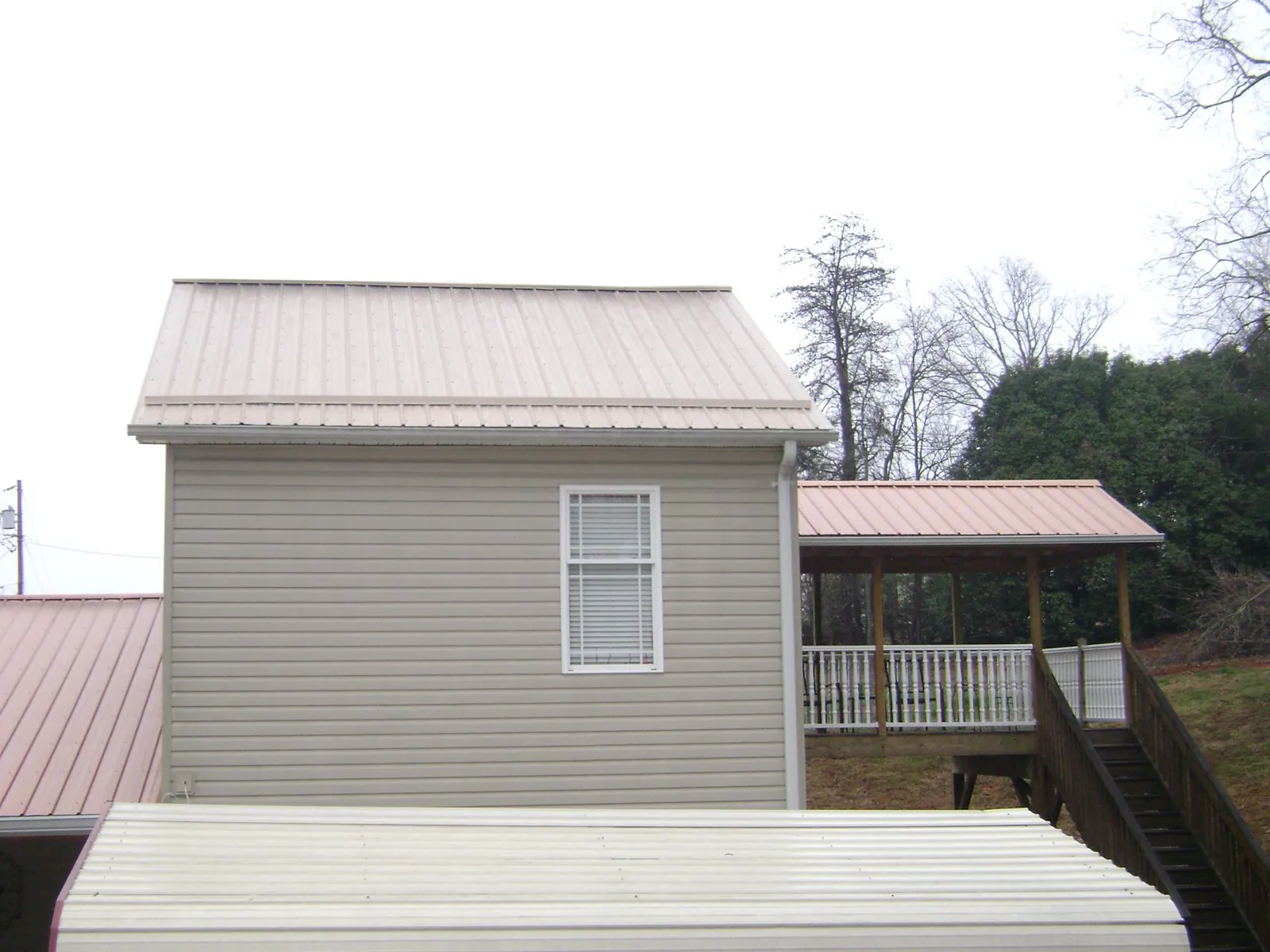Tan metal roofs on a two story addition and attached porch, from a Roof Replacement job in Delaware City
