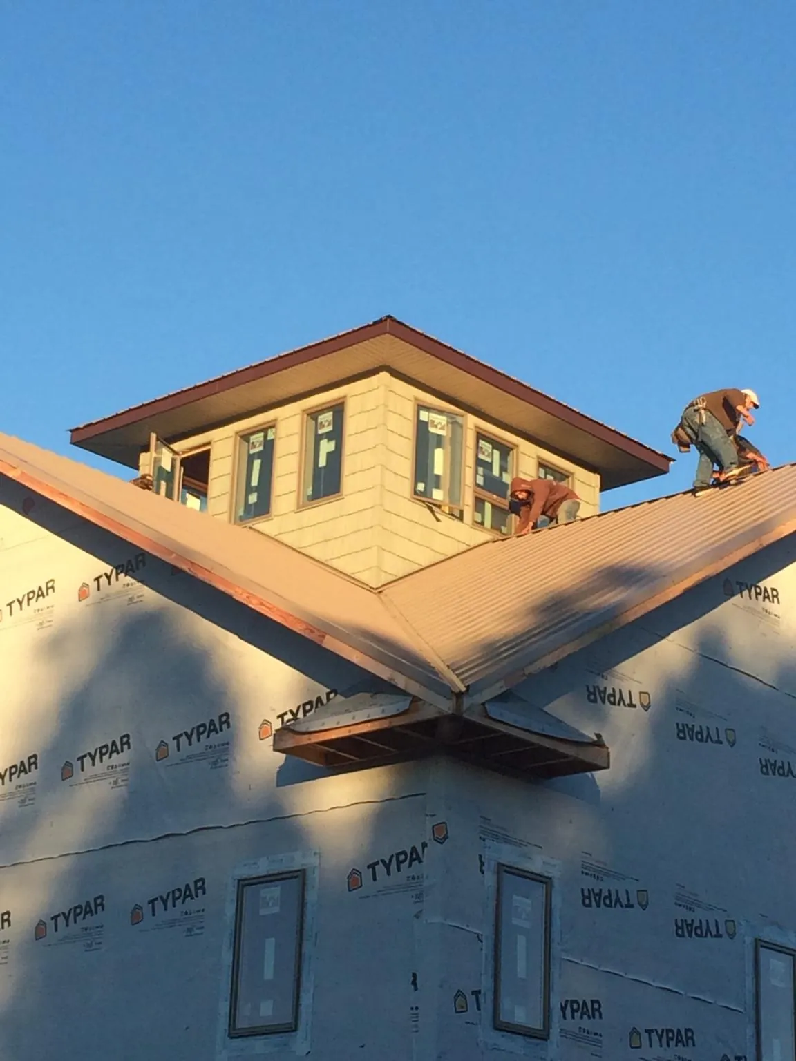 Roofers working around a rooftop cupola on a new metal roof at sunset — Roof Waterproofing in Delaware City by Roofing Brothers